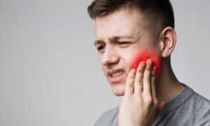 A man holding his cheek because of pain from a dental cyst