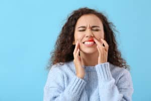 A woman experiencing pain in her gums and teeth from gum disease 