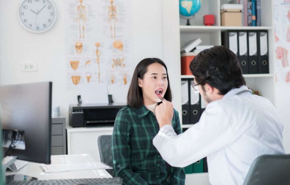 Woman getting an oral exam to check for oral pathologies in doctor’s office.