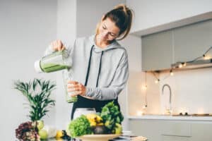 A woman making a green smoothie after dental implant surgery
