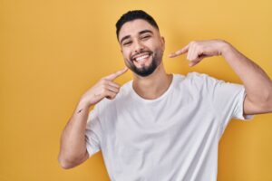 A man pointing to his smile after getting All-on-4 dental implants